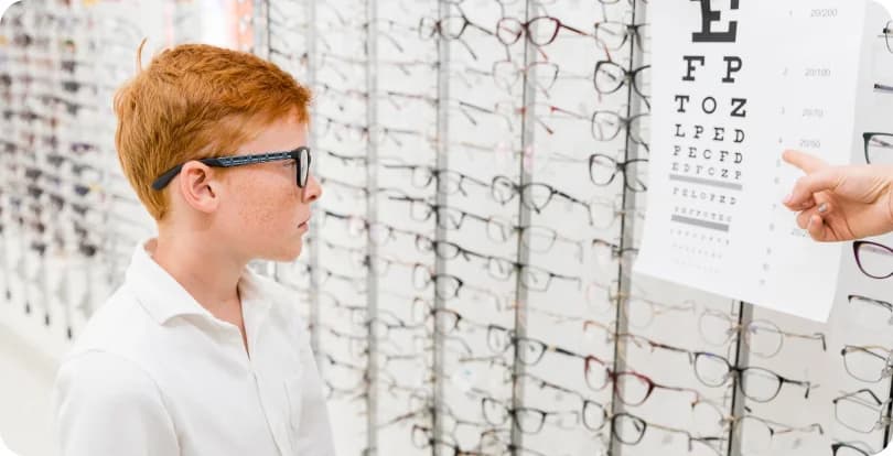 Un opticien fait lire un tableau d'acuité visuelle à un jeune patient